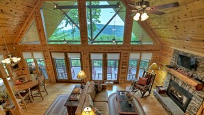 A spacious lodge with a high ceiling, large windows, a fireplace, and a cozy seating area.