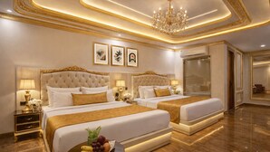 A luxurious hotel room with two large beds, a chandelier, and framed artwork on the wall.