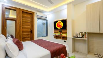 Een moderne hotelkamer met een bed, een televisie, een plank met toiletartikelen en een rode deken.