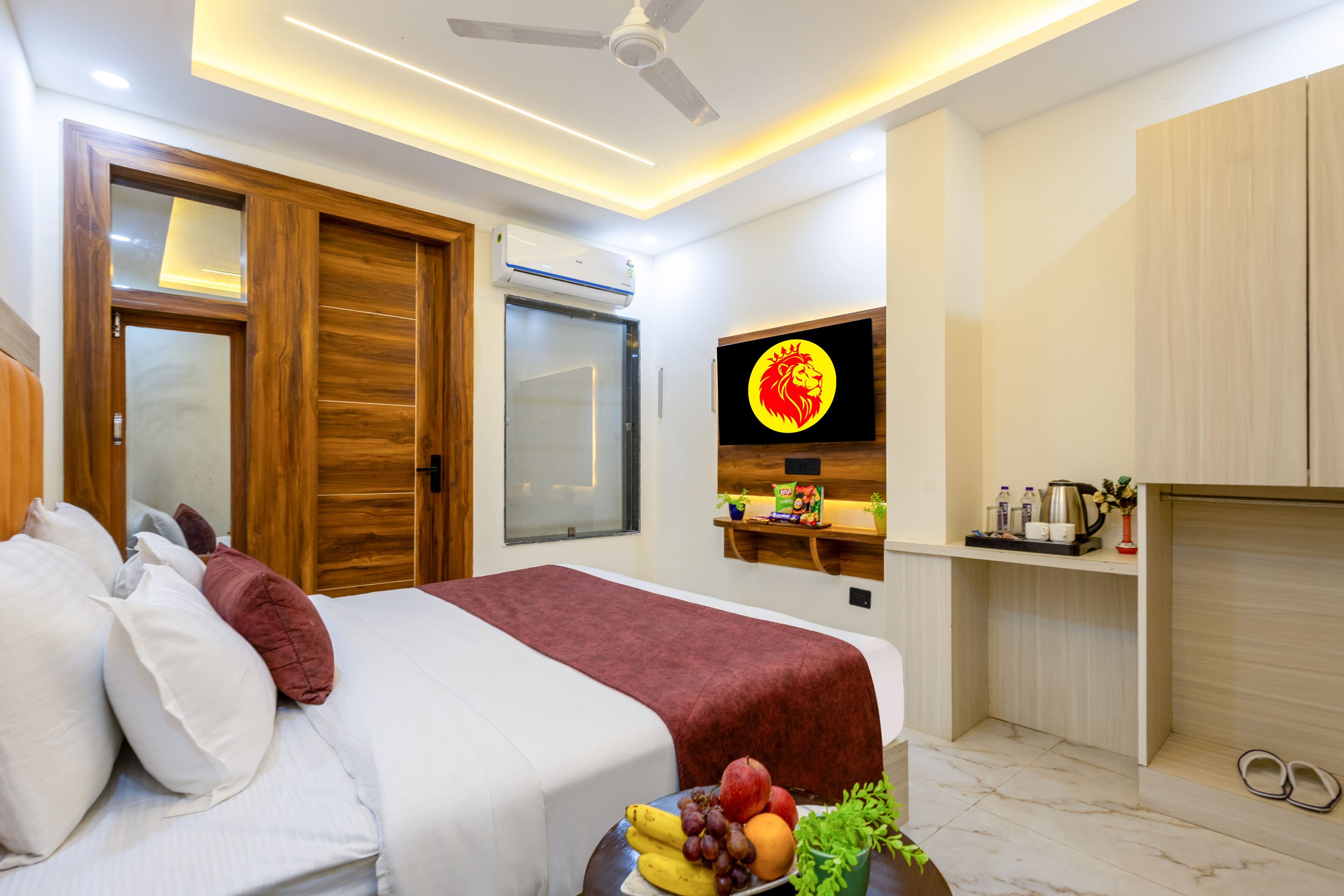Una habitación de hotel moderna con una cama, un televisor, un estante con artículos de aseo y un frutero.