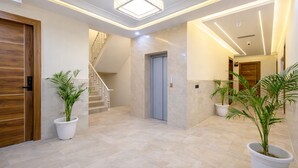 A modern hallway with a marble floor, wooden doors, and potted plants.