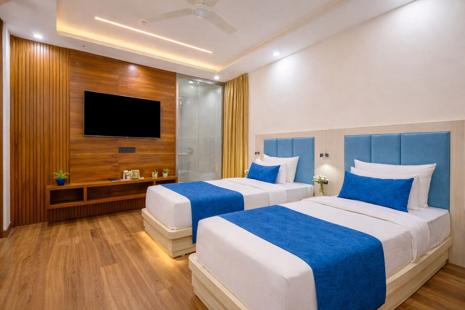 A hotel room with two beds, a TV mounted on the wall, and a wooden panel design.