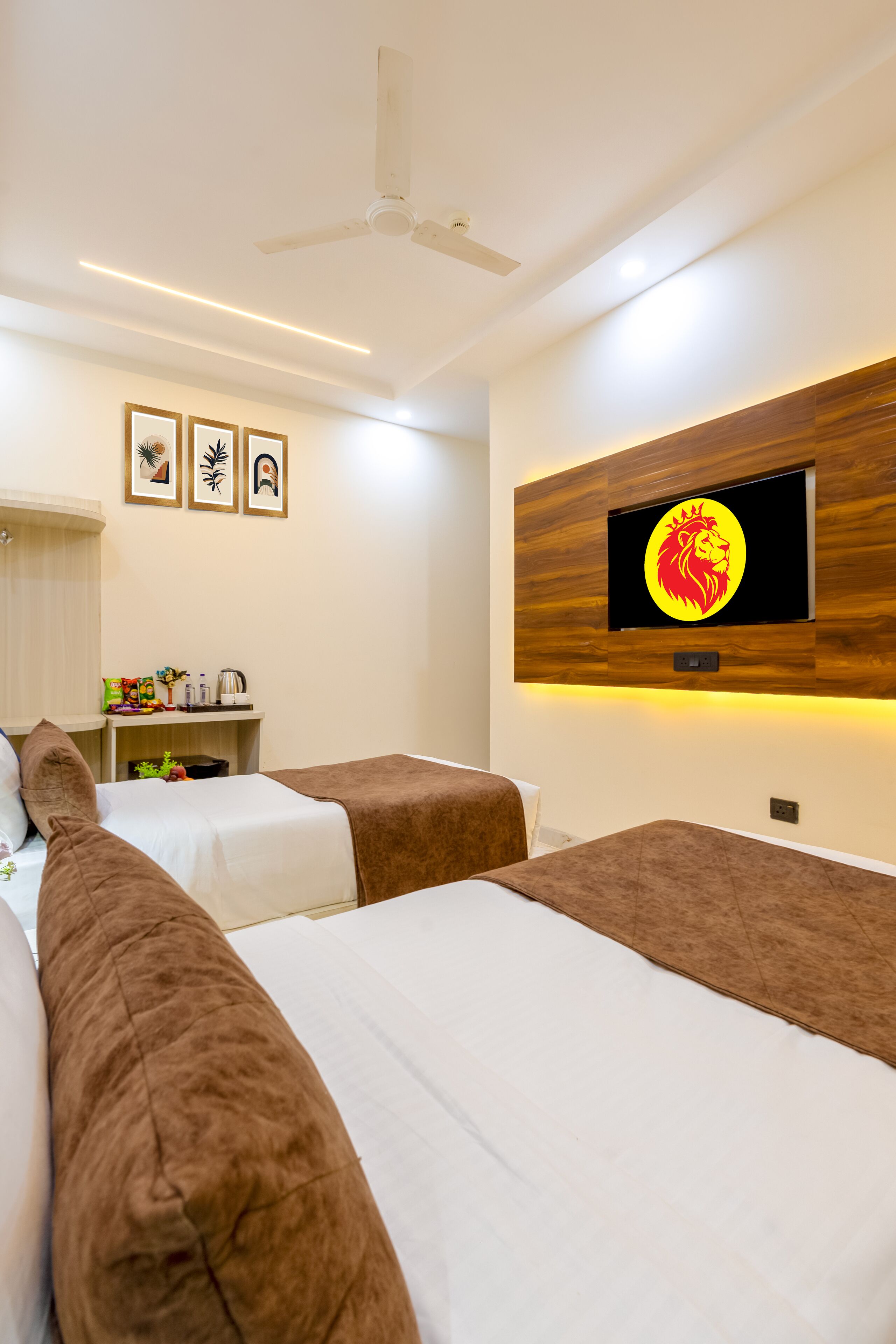 Une chambre d’hôtel avec deux lits, un téléviseur fixé au mur et un ventilateur de plafond.