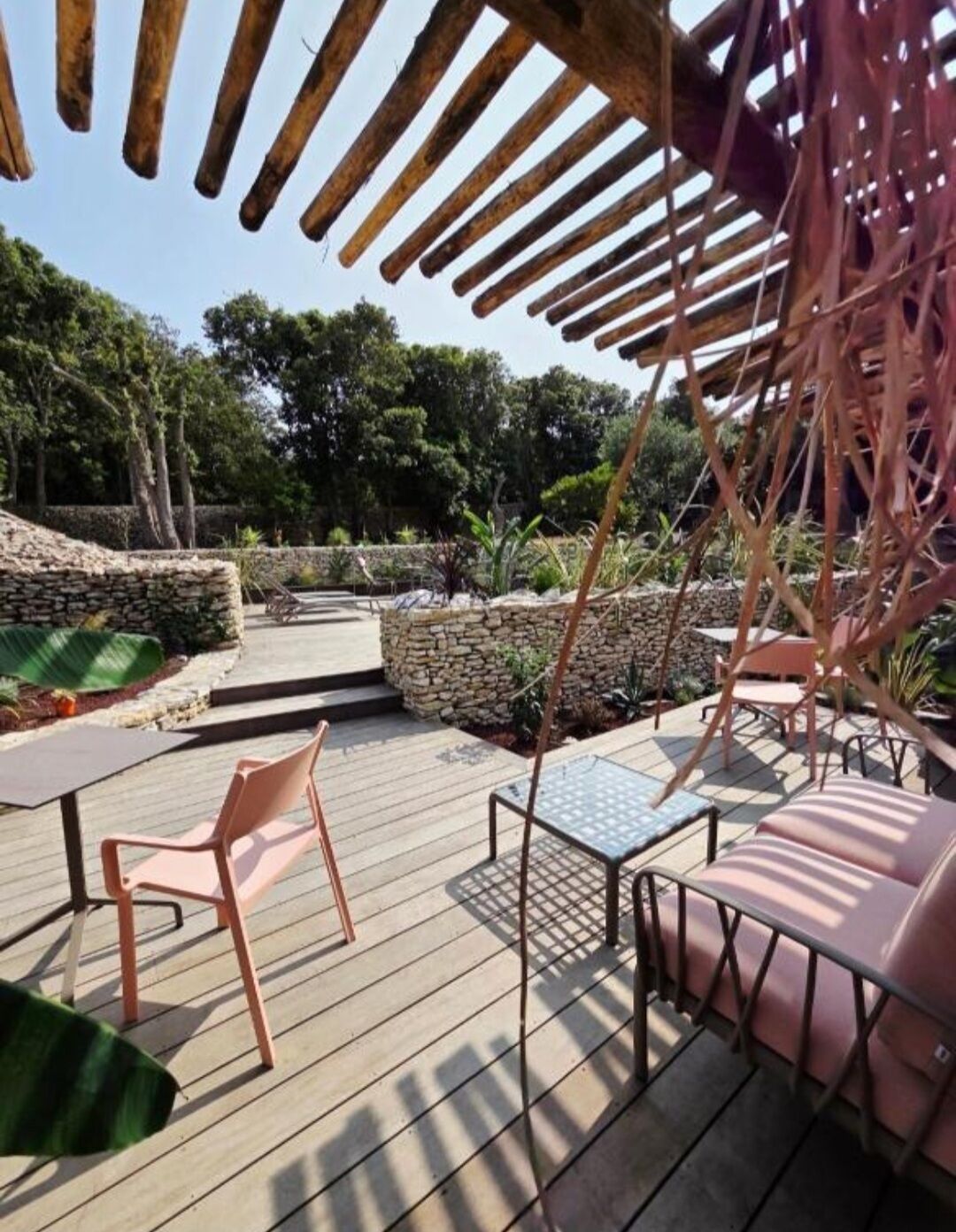 An outdoor patio with wooden flooring, stone walls, and seating areas.