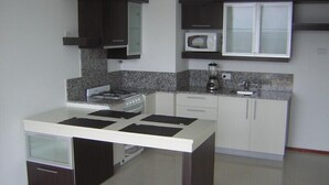 A compact kitchen with a gas stove, microwave, and a blender on the countertop. - Apart Riviera Tower Suites (Villa Carlos Paz)