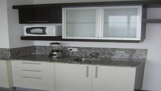 A kitchen with a granite countertop, a blender, a microwave, and white cabinets. - Apart Riviera Tower Suites (Villa Carlos Paz)