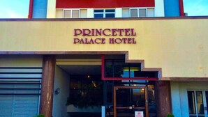 L’entrée de l’hôtel Princess se distingue par sa façade moderne, ses grandes portes vitrées et une enseigne indiquant qu’il s’agit d’un hôtel récemment ouvert.