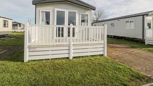 A mobile home with a fenced deck, a small porch, and a garage. - Manor House Gold 2 Bedroom (Maryport)
