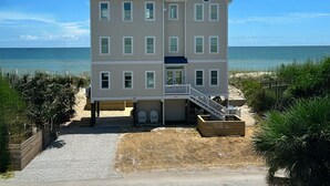 A multi-story beachfront hotel with a balcony, a staircase, and a sandy beach area.