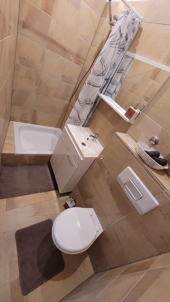 Une salle de bain moderne équipée d’une baignoire, de toilettes, d’un lavabo et d’une douche.