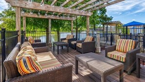 A covered outdoor deck with wicker furniture and a view of a body of water. - Modern 3BR 2.5BTH Terra Verde Home with Private Hot Tub! (Kissimmee)