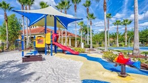 A playground with slides and a covered play area, surrounded by palm trees and a pool. - Modern 3BR 2.5BTH Terra Verde Home with Private Hot Tub! (Kissimmee)