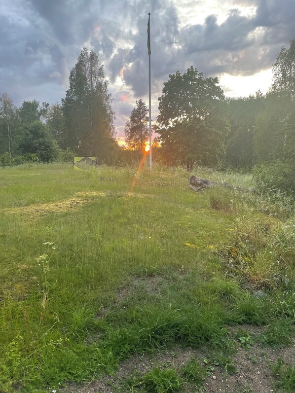 A grassy field with a flagpole and trees in the background. - Cottage in historic Mariefred (Södermanlands län)