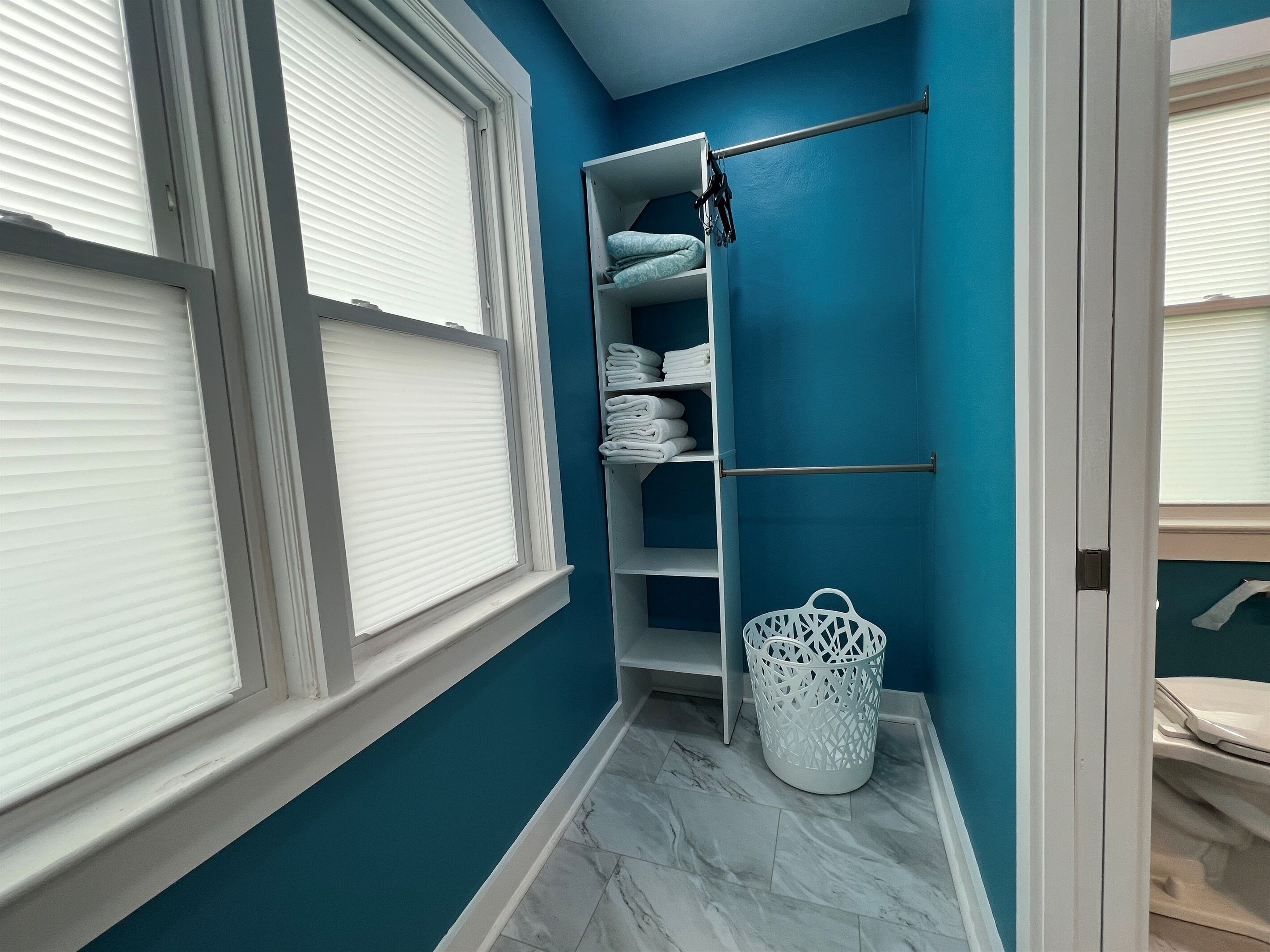 Un baño con pared azul, puerta blanca e inodoro blanco.