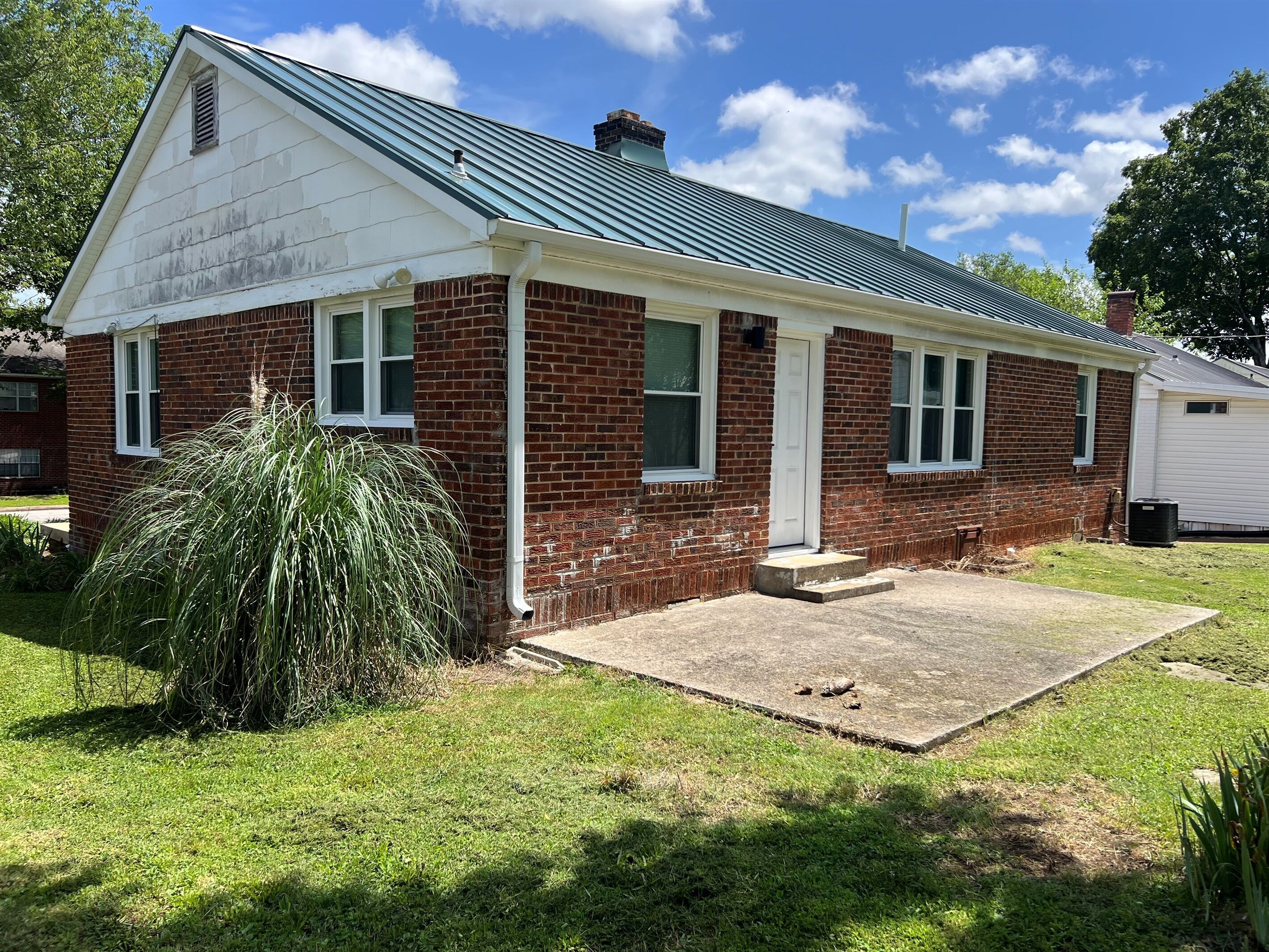 A single-story brick house with a gabled roof and a front porch.