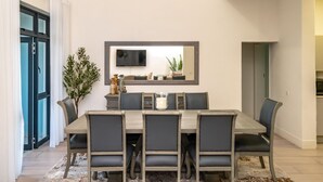 A dining area with a rectangular table, six chairs, a flat-screen TV mounted on the wall, and a potted plant. - Stunning 3 Bedroom House Near Harare Airport -2297 (Harare)