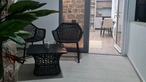 A modern kitchen with white cabinets, a stone accent wall, and a dining area with black wicker chairs and a table. - Sea view Charming 1-bedroom apartment with AC, WiFi in enchanting Tivat (Tivat)