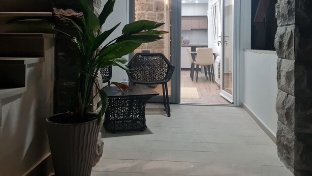 A narrow hallway with a stone wall on one side and a glass door leading to a dining area. There is a potted plant and a small table with chairs in the hallway. - Sea view Charming 1-bedroom apartment with AC, WiFi in enchanting Tivat (Tivat)
