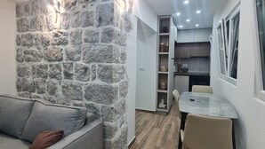 A modern kitchen with built-in appliances, a dining area with a marble table, and a stone accent wall. - Sea view Charming 1-bedroom apartment with AC, WiFi in enchanting Tivat (Tivat)