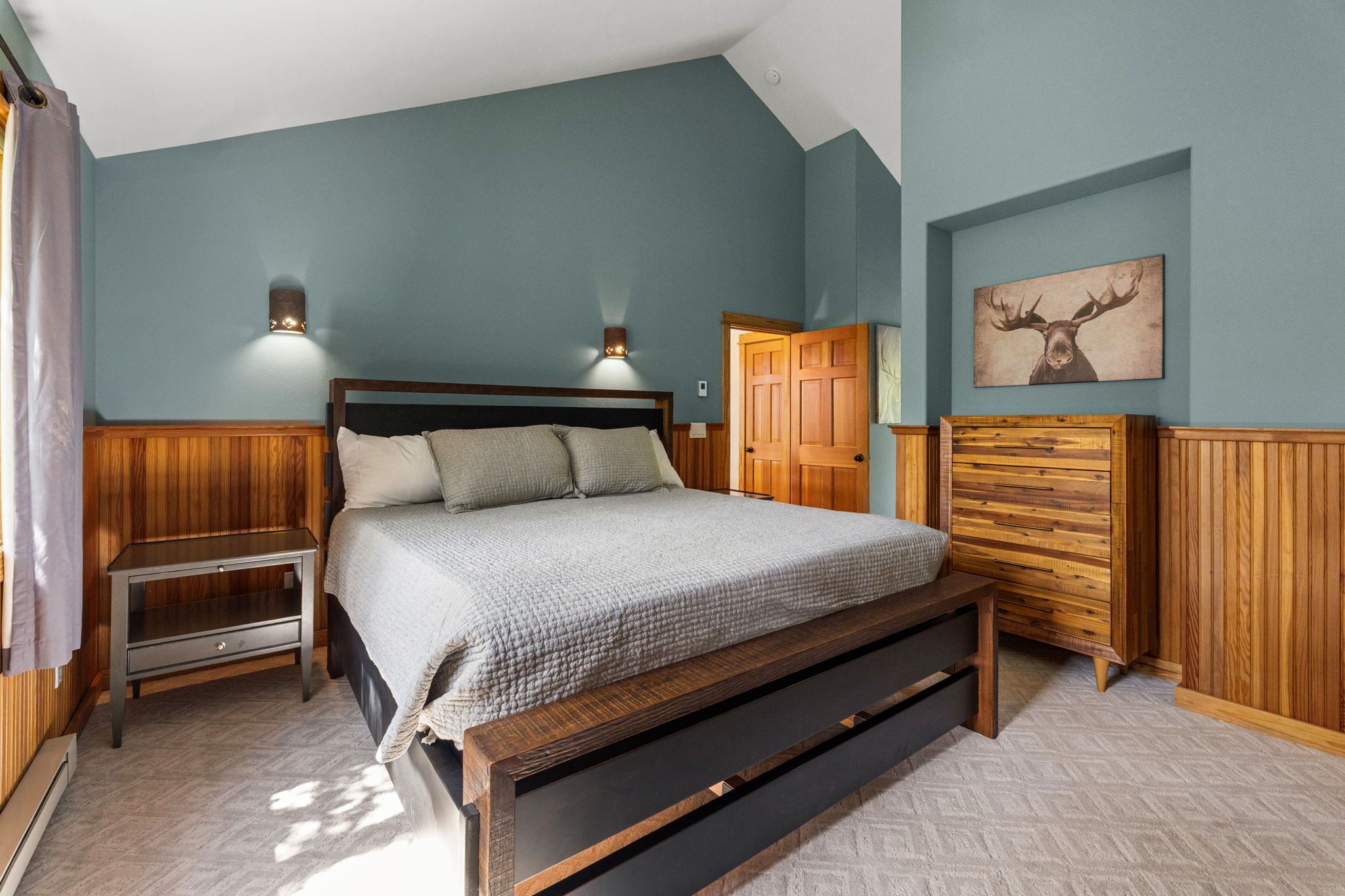 Ein Schlafzimmer mit einem hölzernen Bett, zwei Nachttischen, einem Kleiderschrank und einer Wandleuchte.