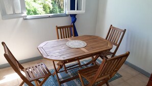 A wooden dining table with six chairs, a patterned rug, and a window with curtains. - House, located on the Guadeloupe coast. 25min. from the volcano. (Vieux-Fort)