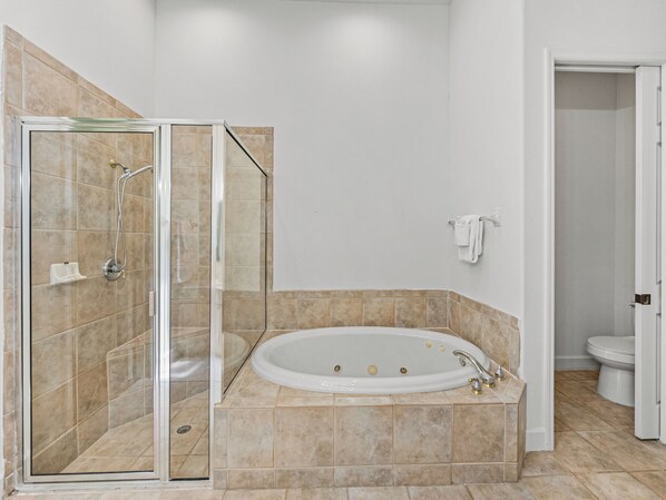 Et badeværelse med en glasafskærmet brusekabine, et fristående badekar og et toilet.