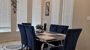 A dining area with a wooden table, dark blue upholstered chairs, and a patterned rug. - Family-Friendly 5BR Home, Game Room + Large Backyard! with AC, WiFi in 77407 (Richmond)