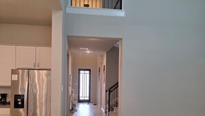 A spacious living area with a modern kitchen, a sofa, and a staircase leading to an upper floor. - Family-Friendly 5BR Home, Game Room + Large Backyard! with AC, WiFi in 77407 (Richmond)
