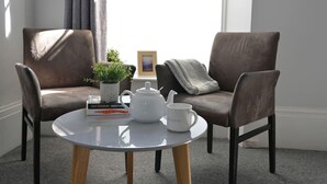 A cozy seating area with two brown armchairs, a small round table with a white teapot, a mug, and a potted plant. - Spacious Penthouse | Central  Location | 3 Doubles (Plymouth)