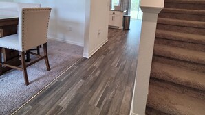 A spacious living area with a carpeted floor, a dining table with chairs, and a staircase leading to another level. - Spacious 4-bedroom Mas in Delightful Palm Coast with AC, WiFi (Palm Coast)