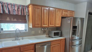 A kitchen with wooden cabinets, a stainless steel refrigerator, a dishwasher, and a toaster. - Three Eagle Nest - Mountains of Fun in Lake City, Colorado (Lake City)