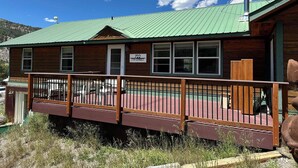 A wooden building with a green roof, a sign reading "722 7th Street," and a wooden deck with a metal railing. - Three Eagle Nest - Mountains of Fun in Lake City, Colorado (Lake City)