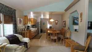 A spacious living area with a sofa, dining table, and chairs, a kitchen with wooden cabinets, and a TV mounted on the wall. - Three Eagle Nest - Mountains of Fun in Lake City, Colorado (Lake City)