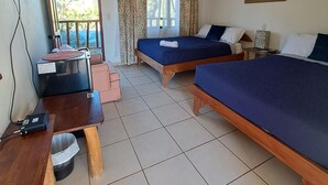 A room with two beds, a desk, a ceiling fan, and a window with curtains. - Georgi, Junquillal (Veintisiete de Abril)