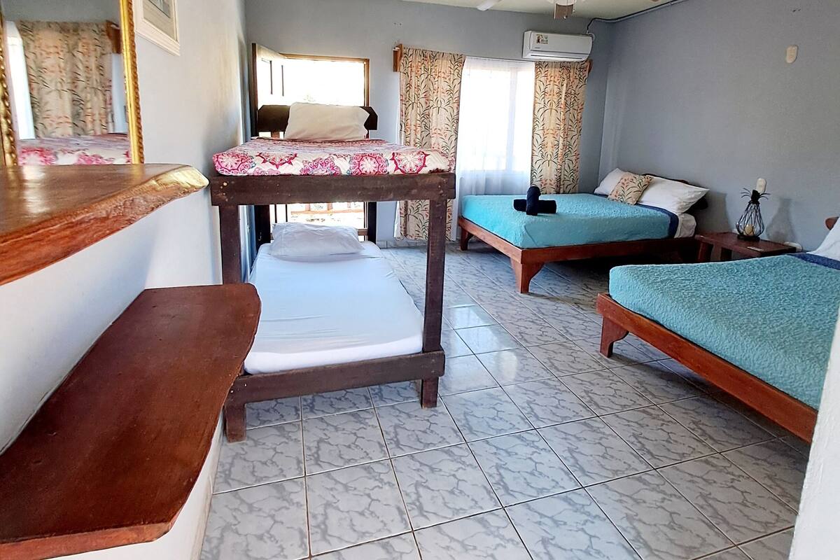 A room with two beds, a ceiling fan, and a large mirror.