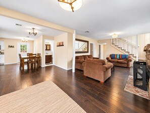 A spacious living area with a dining table, sofas, and a staircase. - Hibernation Haven (Big Bear Lake)