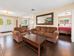 A living room with a brown sofa set, a wooden coffee table, and a large mirror on the wall. - Hibernation Haven (Big Bear Lake)