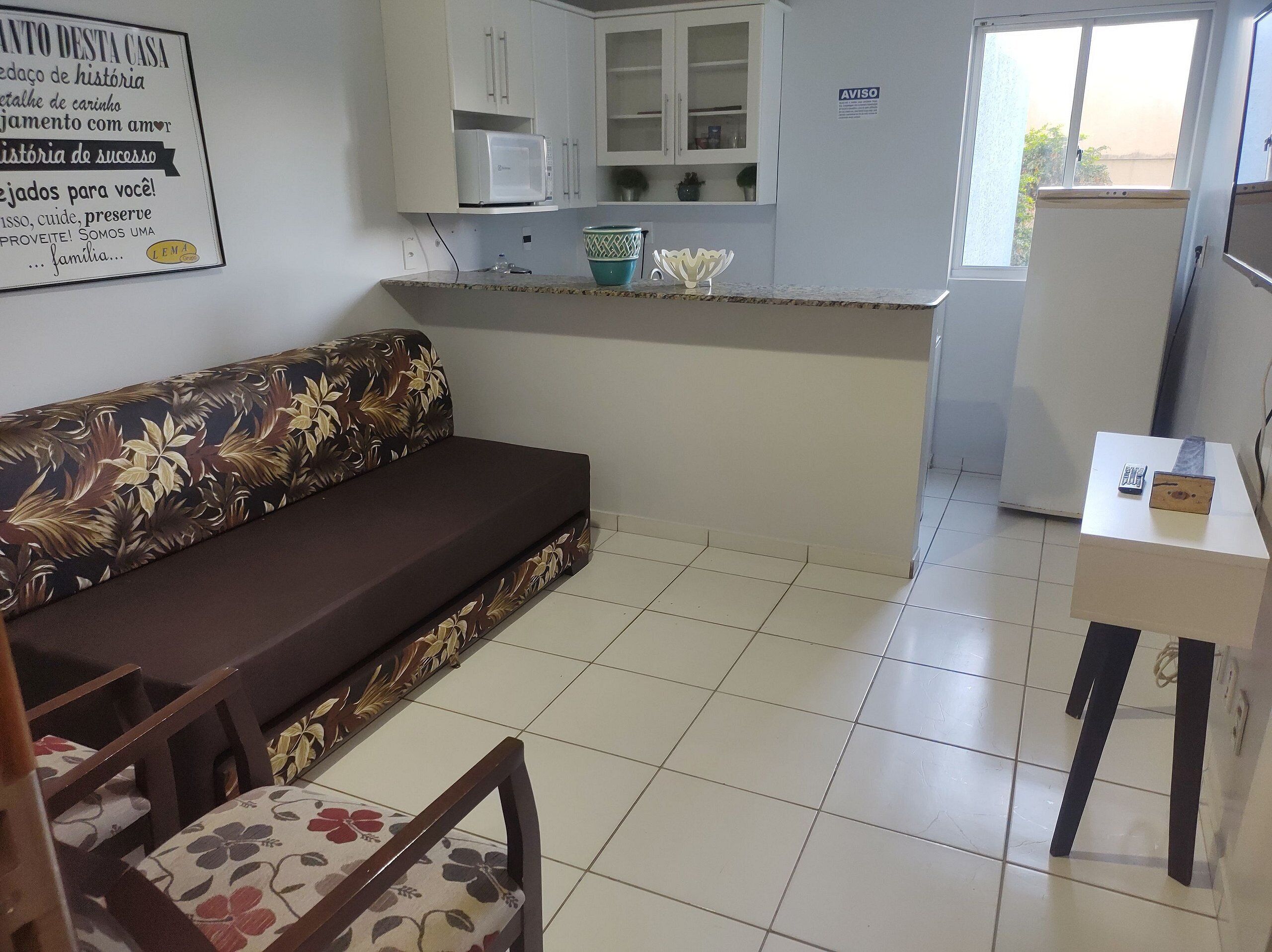 Un espacio habitable compacto con un sofá, una mesita y una kitchenette.