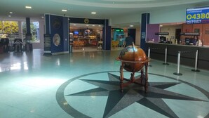 Un lobby amplio con un diseño de piso en forma de brújula, una cafetería y un mostrador con un letrero del número de teléfono.
