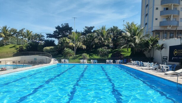Una piscina azul cristalina con sillas de descanso y una valla.