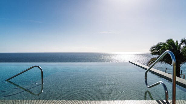 An infinity pool with clear blue water and a view of the ocean. - Acqua Residence VIII – Sea View and Pool (Funchal)