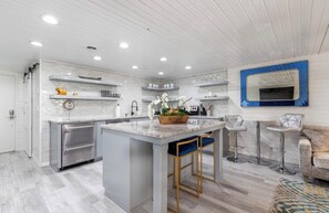 A modern kitchen with a central island, stainless steel appliances, and a bar area with stools.