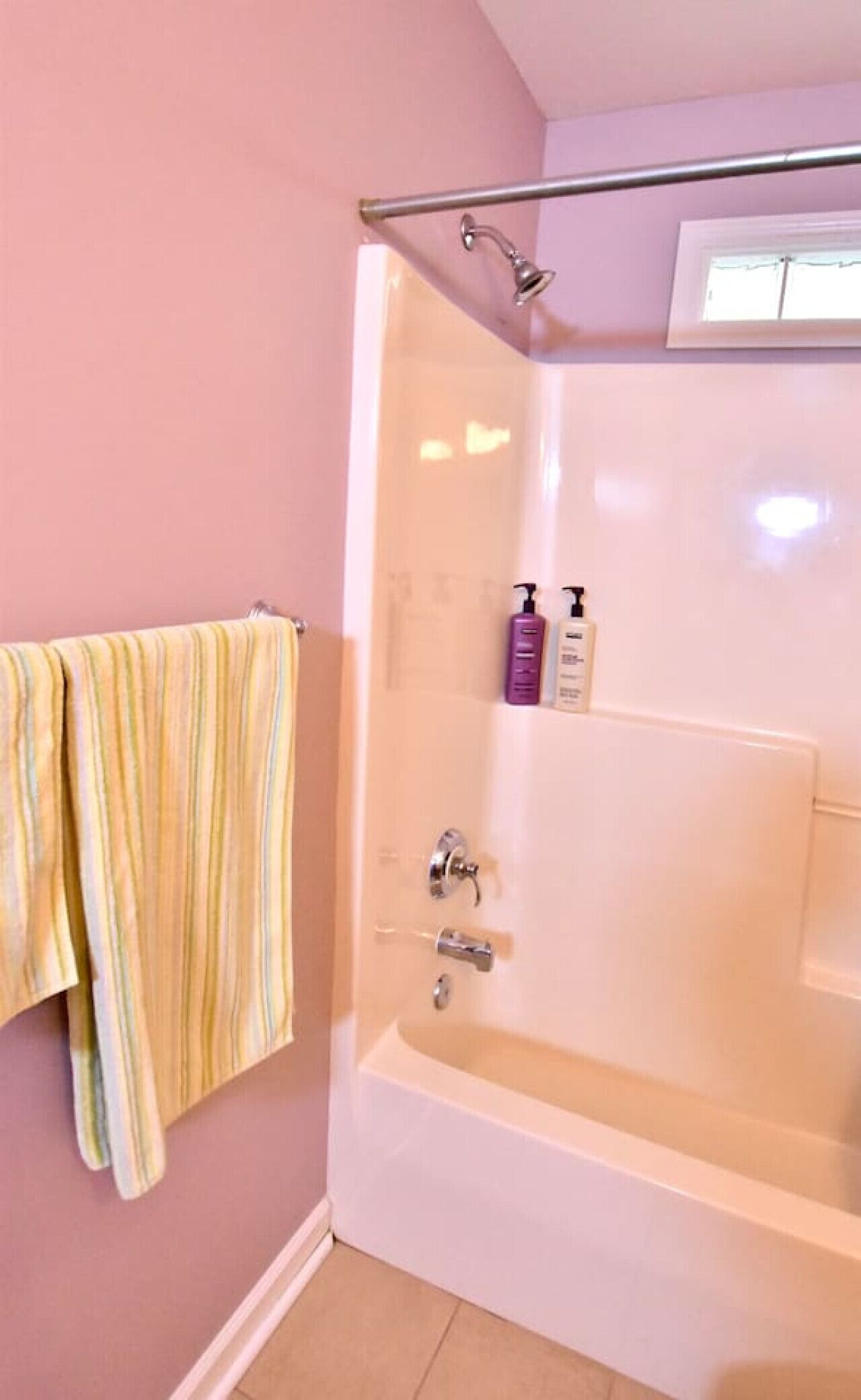 A bathroom with a bathtub, a shower, and a towel rack with striped towels.