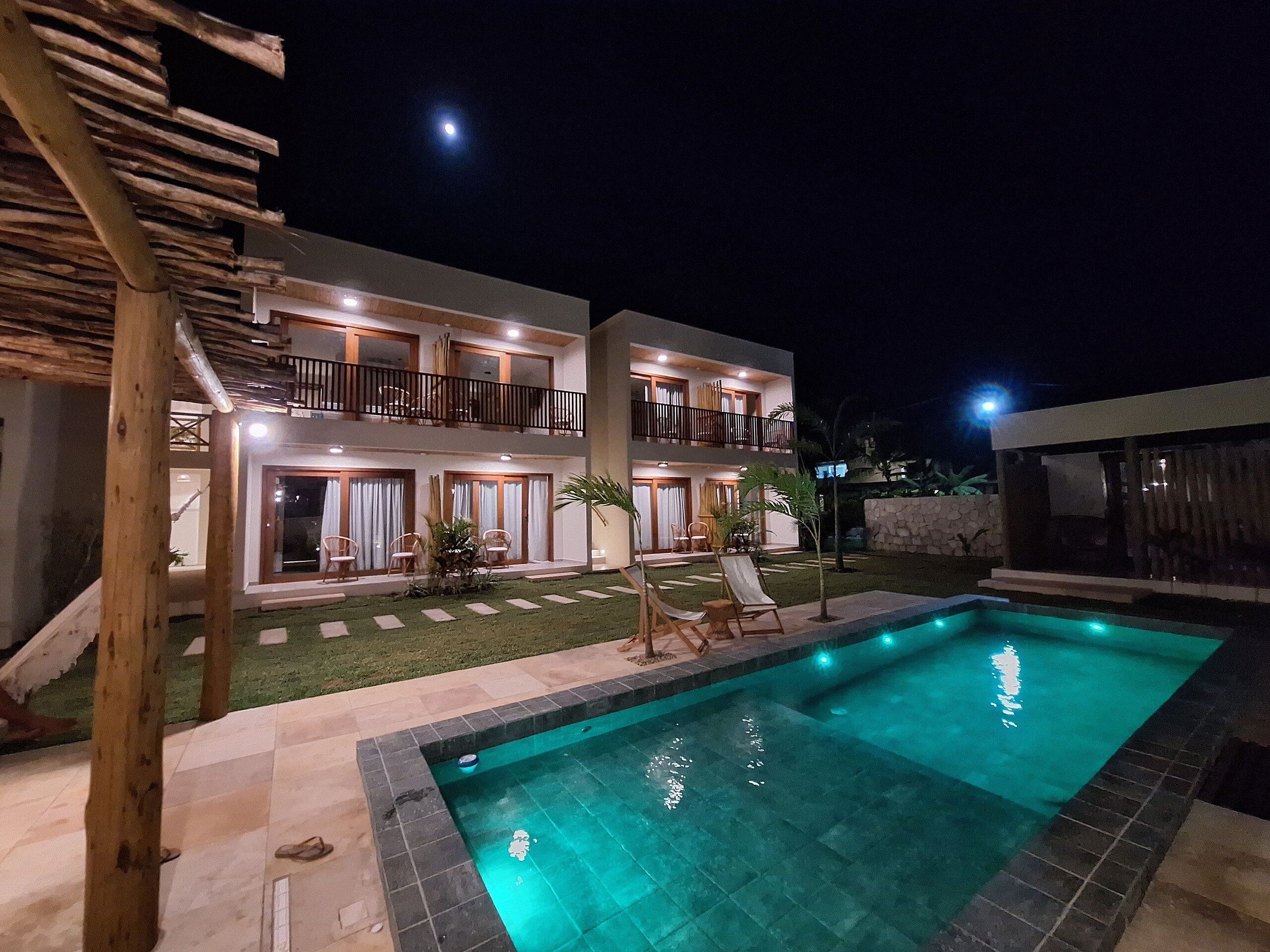 A two-story building with a swimming pool, outdoor seating, and a well-lit balcony.