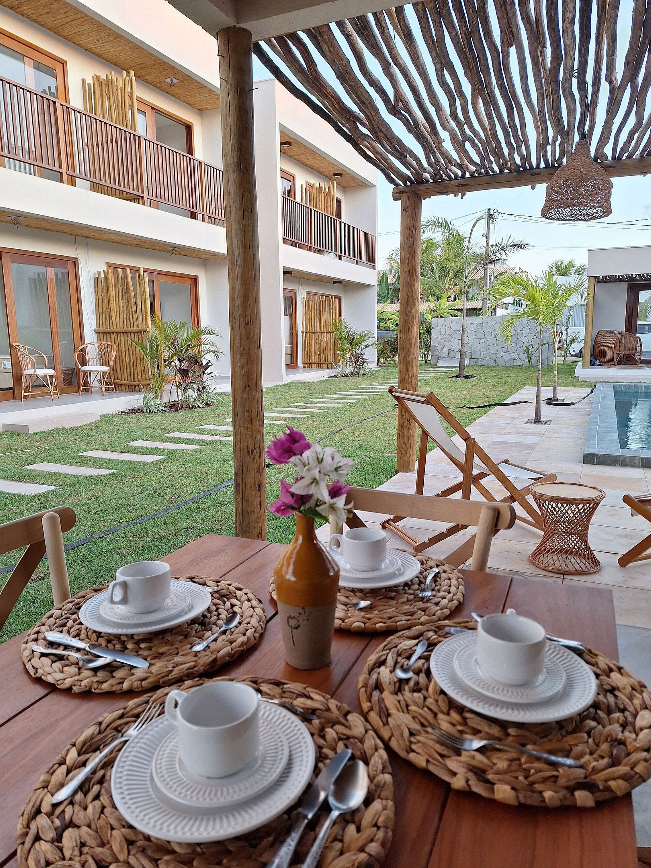 An outdoor dining area with wooden furniture, woven placemats, and a table set for two.