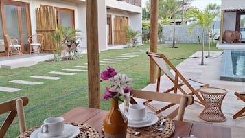 An outdoor dining area with wooden furniture, woven placemats, and a table set for two.