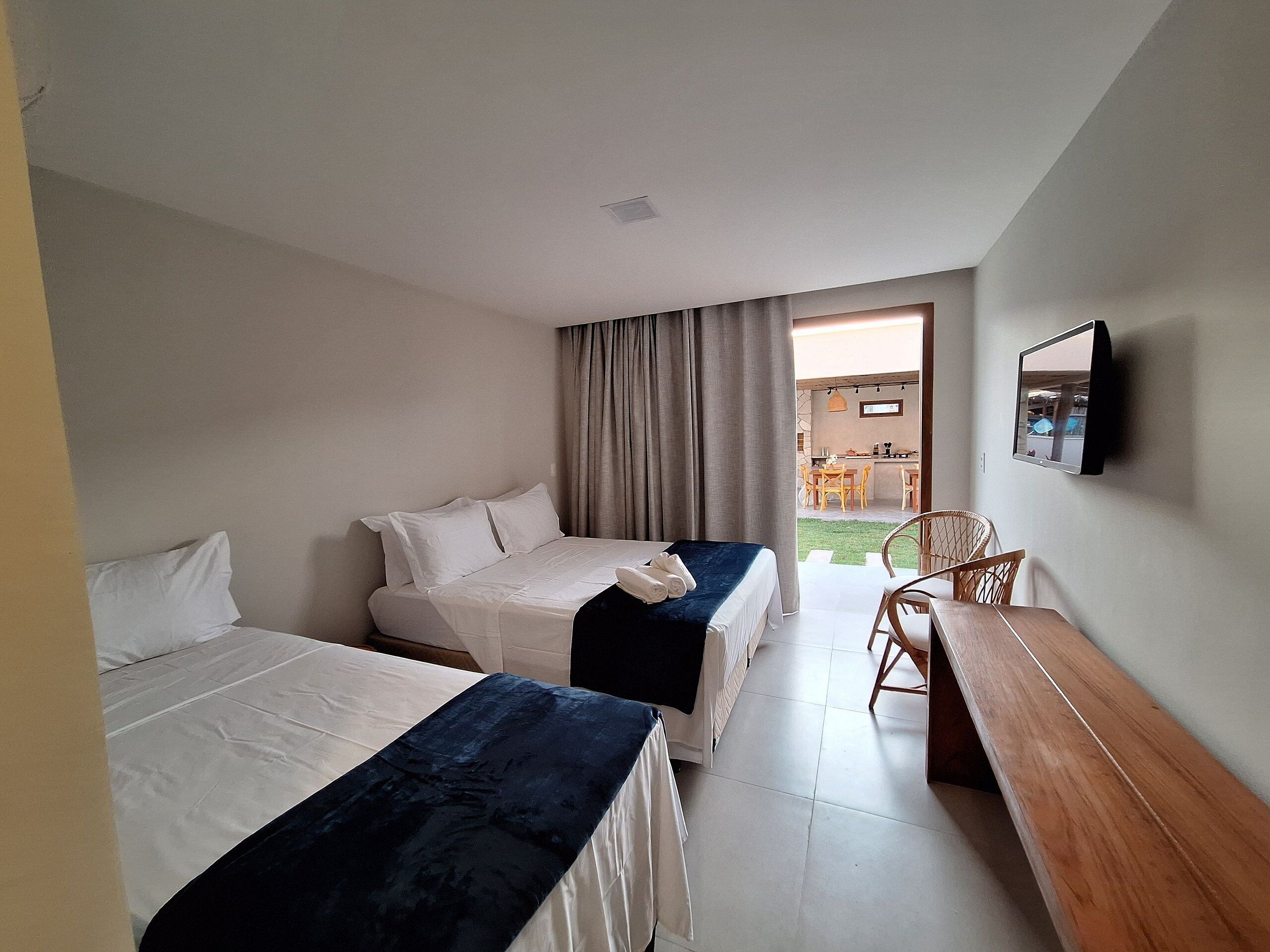 Une chambre d’hôtel avec deux lits, un bureau, une chaise et un téléviseur fixé au mur.