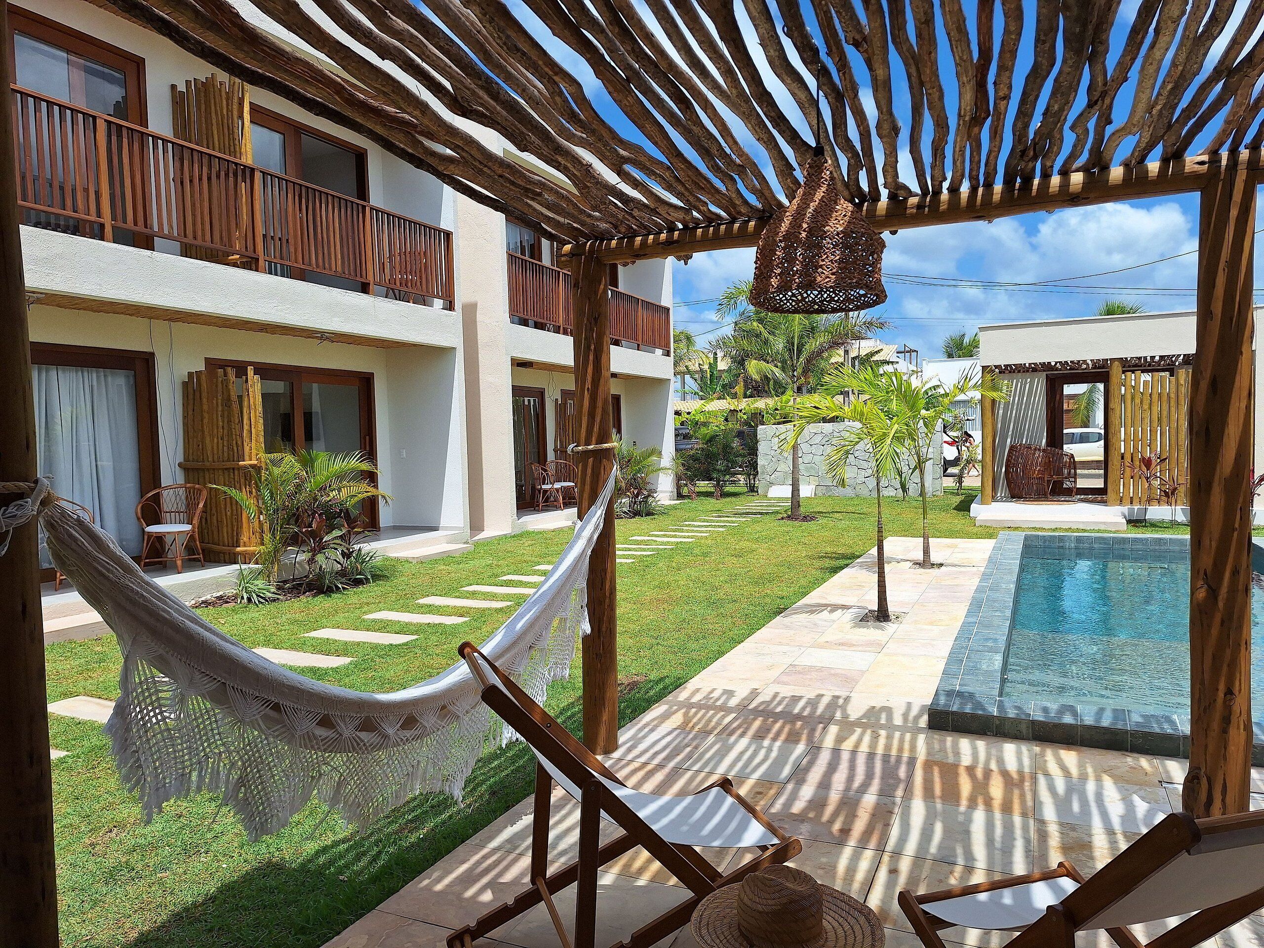A poolside area with a hammock, lounge chairs, and a pergola with a hanging light fixture.