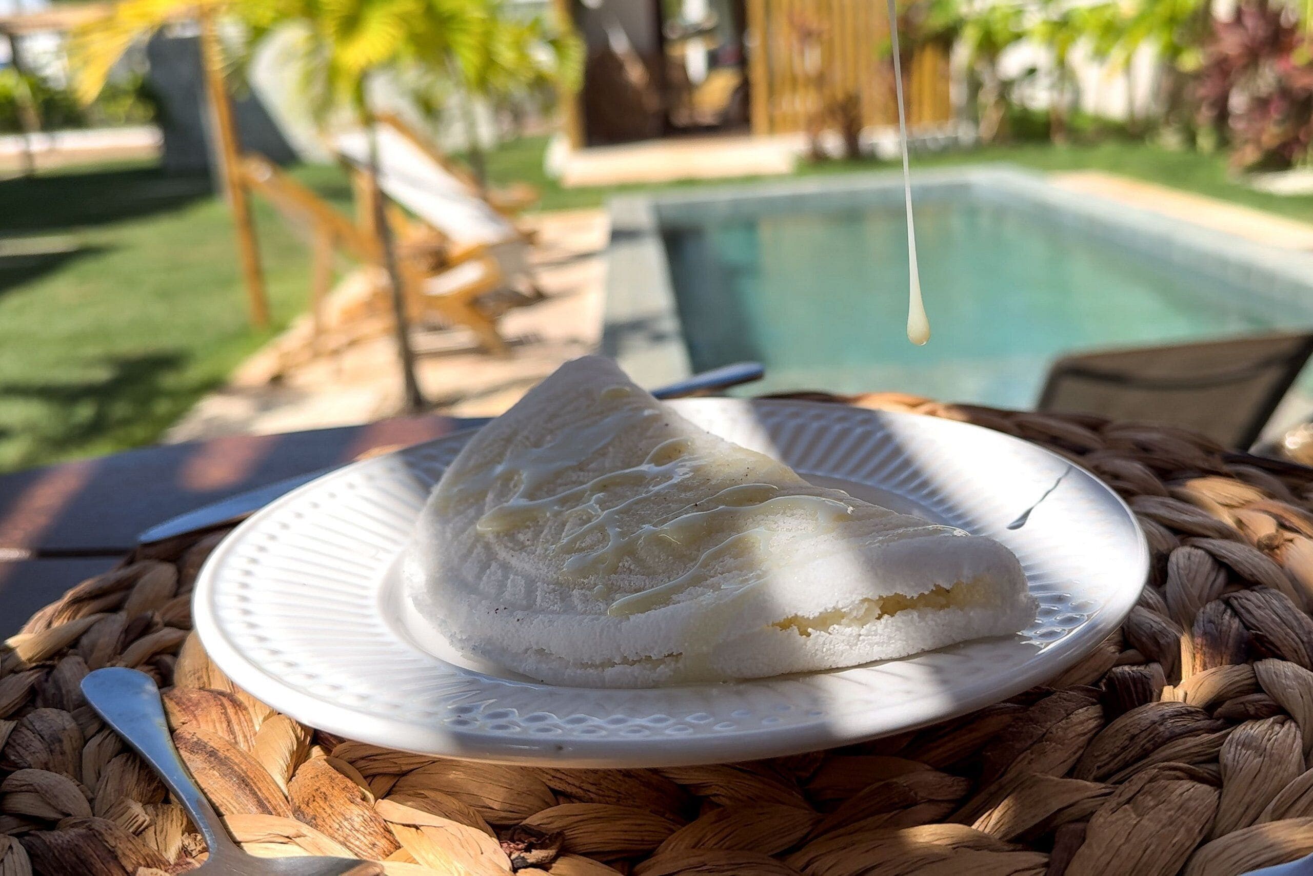 A dessert on a plate with a pool and outdoor seating in the background.