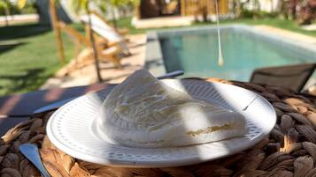 A dessert on a plate with a pool and outdoor seating in the background.